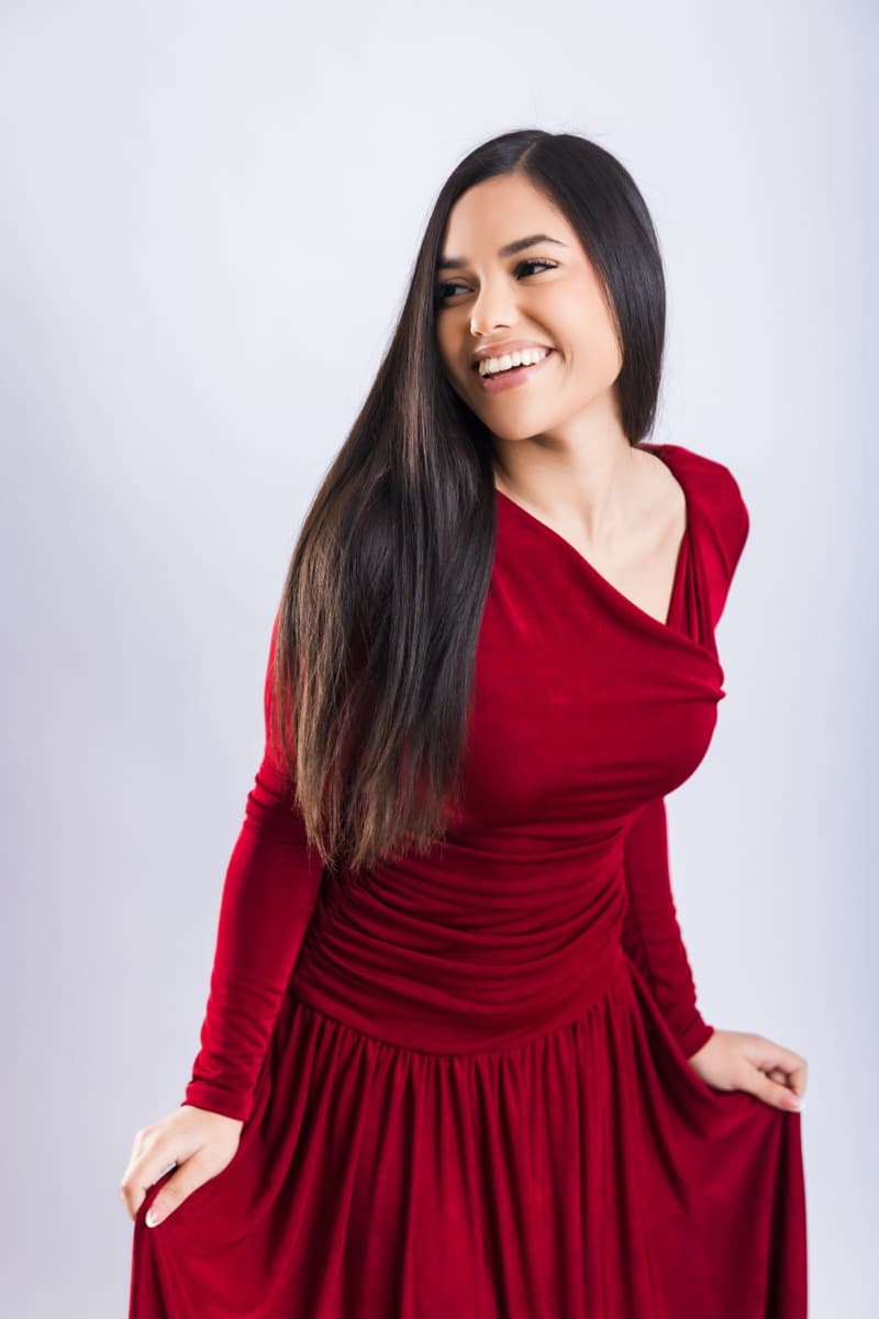 Retrato de estudio de Elizabet Maria sonriendo, con vestido rojo de terciopelo