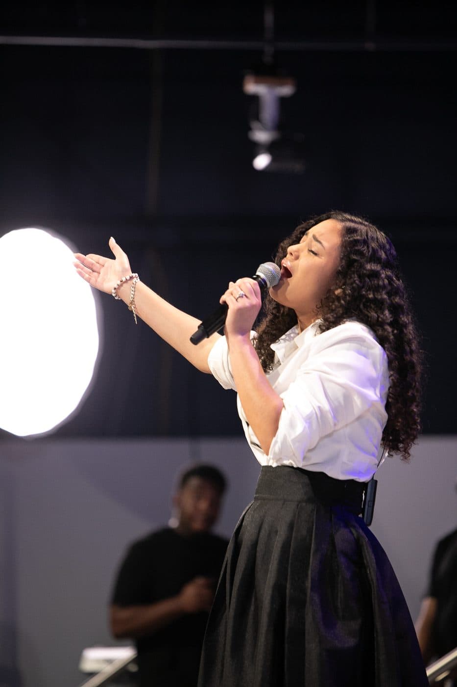 Elizabet Maria cantando con el brazo extendido en adoración