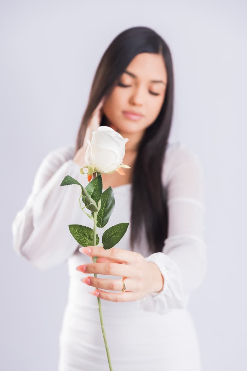 Elizabet Maria extendiendo una rosa blanca hacia la cámara